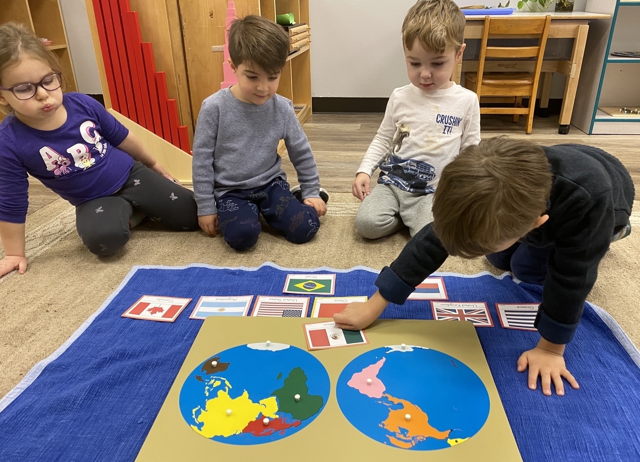 Children gathered on the floor around a world map puzzle