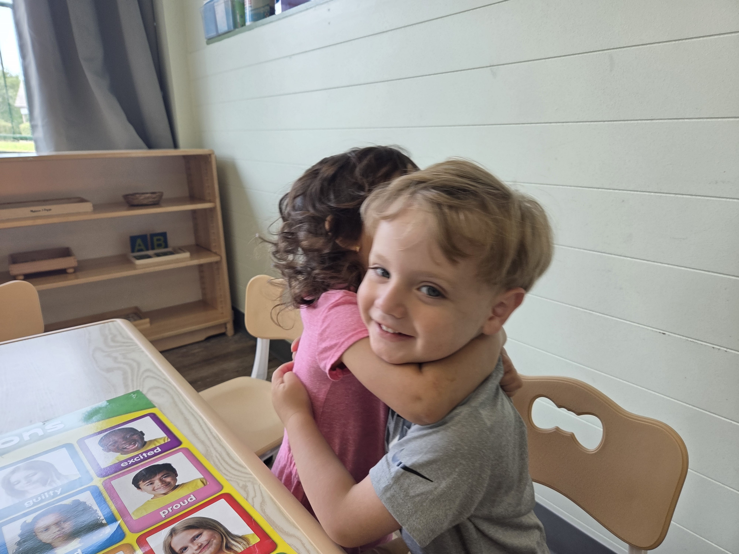 A teacher hugging a smiling child