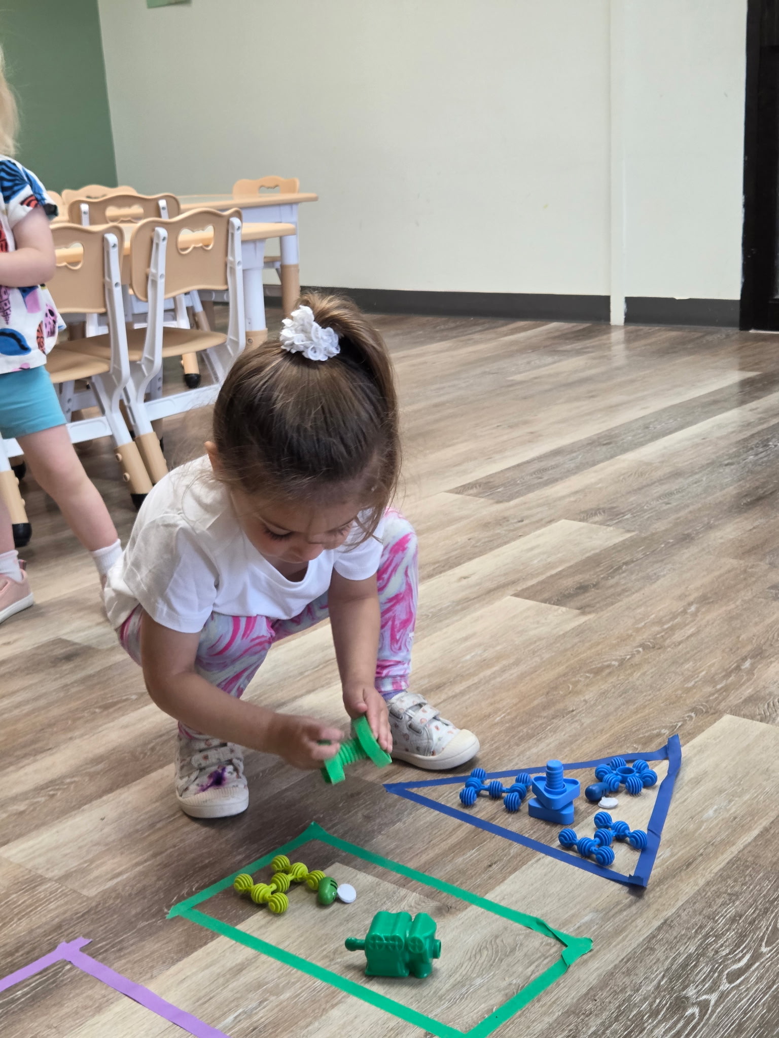 A toddler placing Montessori materials on a work mat